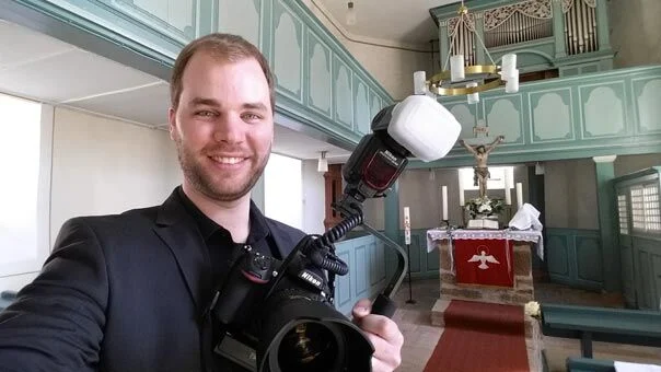 Fotograf mit Kamera und Blitz in der Kirche Hatzbach vor dem Altar