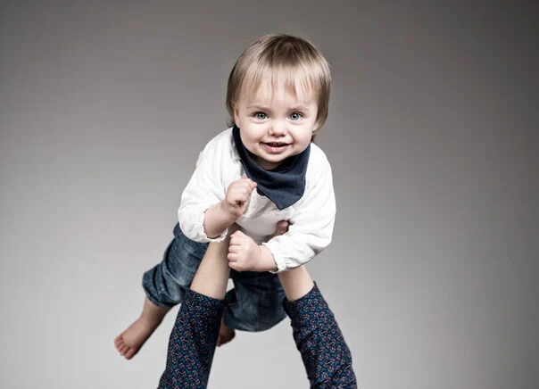 Kleinkind lacht | Peter Lauritis Photography Wiedersehen im Fotostudio: lachendes Mädchen auf den Füßen eines Erwachsenen