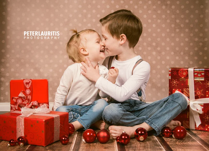 Geschwister mit Geschenken | Peter Lauritis Photography Weihnachtsgruß 2015: zwei Geschwister lachen zwischen roten Geschenken und Kugeln