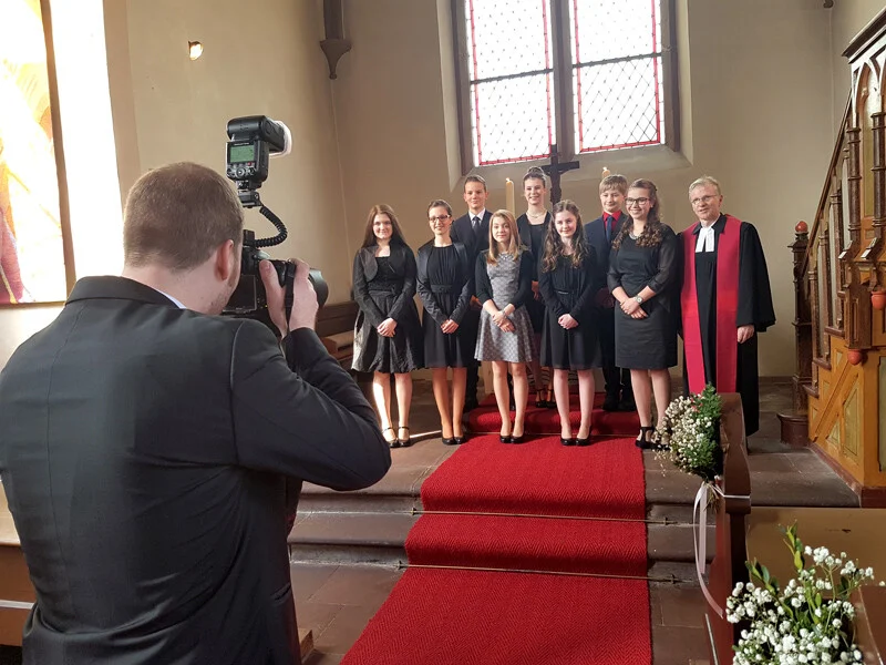 Konfirmationsfotos in Speckswinkel: Fotograf fotografiert Konfirmanden mit Pfarrer vor dem Altar