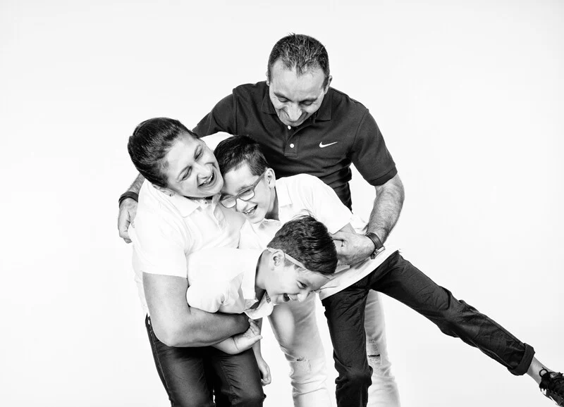 Witzige Familienfotos | Peter Lauritis Photography Witzige Familienfotos: Vater hält Sohn in der Luft, Mutter und Bruder lachen, schwarz-weiß
