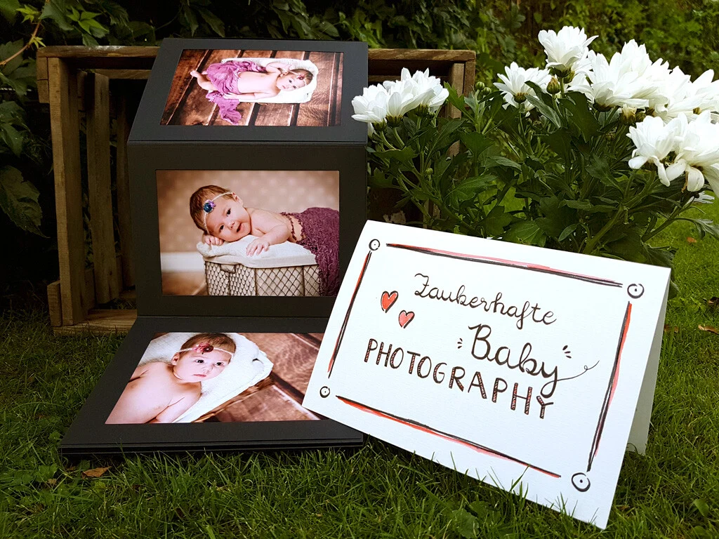 Zauberhafte Babyfotografie: Babyfotos in schwarzen Aufstellern neben weißen Blumen