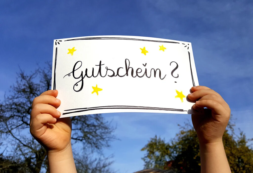 Gutschein-Karte | Peter Lauritis Photography Last-Minute-Weihnachtsgeschenk: Kinderhände halten eine Gutschein-Karte in den blauen Himmel