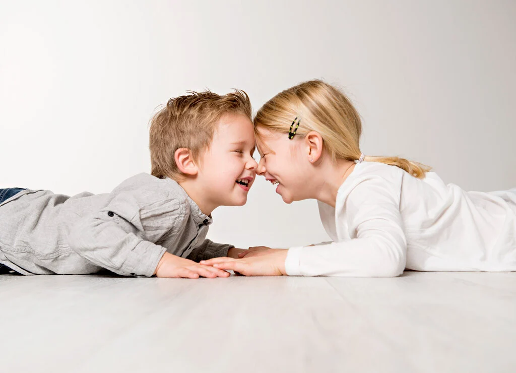 Geschwister Stirn an Stirn | Peter Lauritis Photography Geschwisterfotos im Fotostudio: Bruder und Schwester liegen lachend Stirn an Stirn