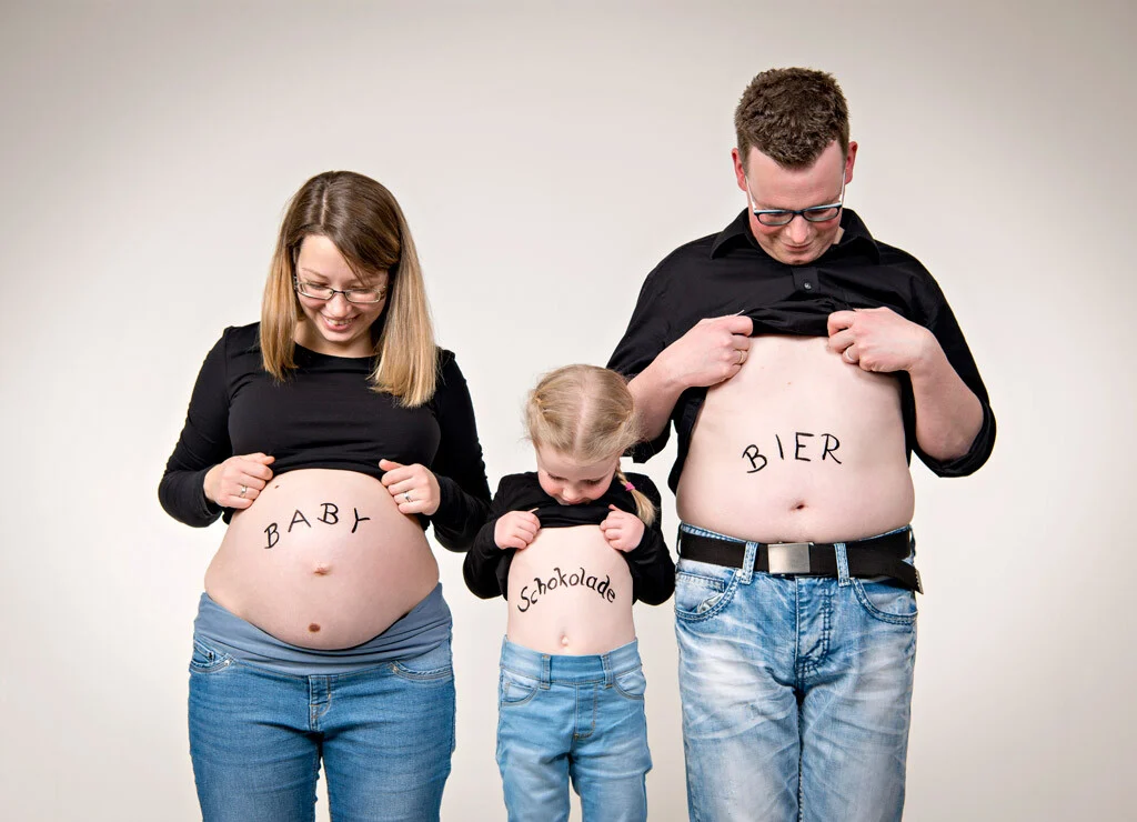 Baby, Bier, Schokolade | Peter Lauritis Photography Babybauchfoto mit Aufschrift: Familie mit Baby, Schokolade und Bier auf den Bäuchen