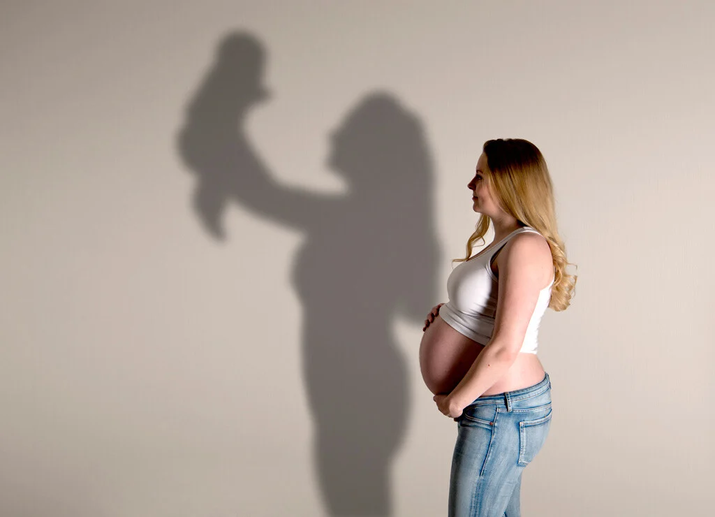 Babybauch mit Schatten | Peter Lauritis Photography Babybauchfoto mit Schatten: Schwangere im Profil, ihr Schatten an der Wand hebt ein Baby hoch