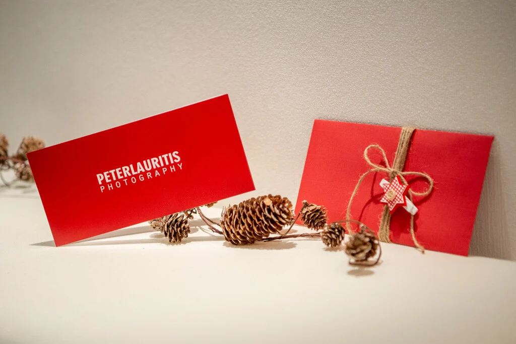 Gutschein im Umschlag | Peter Lauritis Photography Gutschein für jede Jahreszeit: rote Karte mit Logo und roter Umschlag mit Schleife und Tannenzapfen