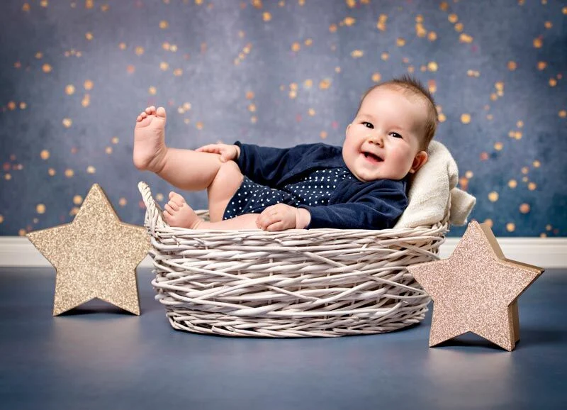 Baby mit Sternen | Peter Lauritis Photography Weihnachtliche Babyfotos: lachendes Baby im Weidenkorb zwischen zwei goldenen Sternen