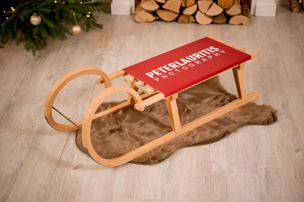 Holzschlitten-Gewinnspiel: Holzschlitten mit rotem Logo-Sitz auf einem braunen Fell