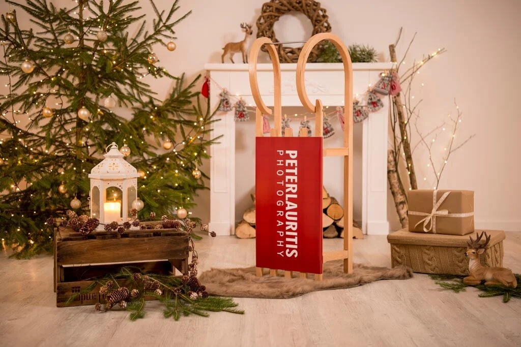 Holzschlitten in weihnachtlicher Kulisse mit Tannenbaum, Laterne und Geschenken