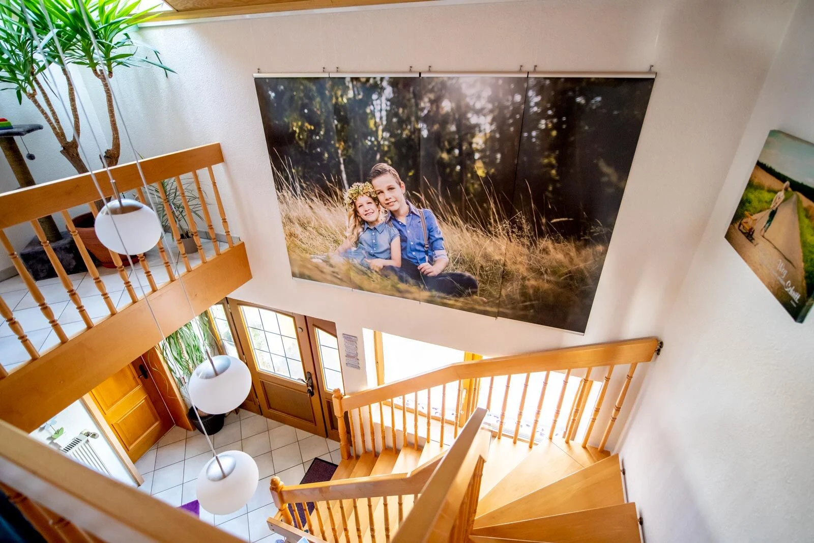Großformat-Fotodrucke: riesiges Foto zweier Geschwister im Gras über einem hellen Treppenhaus