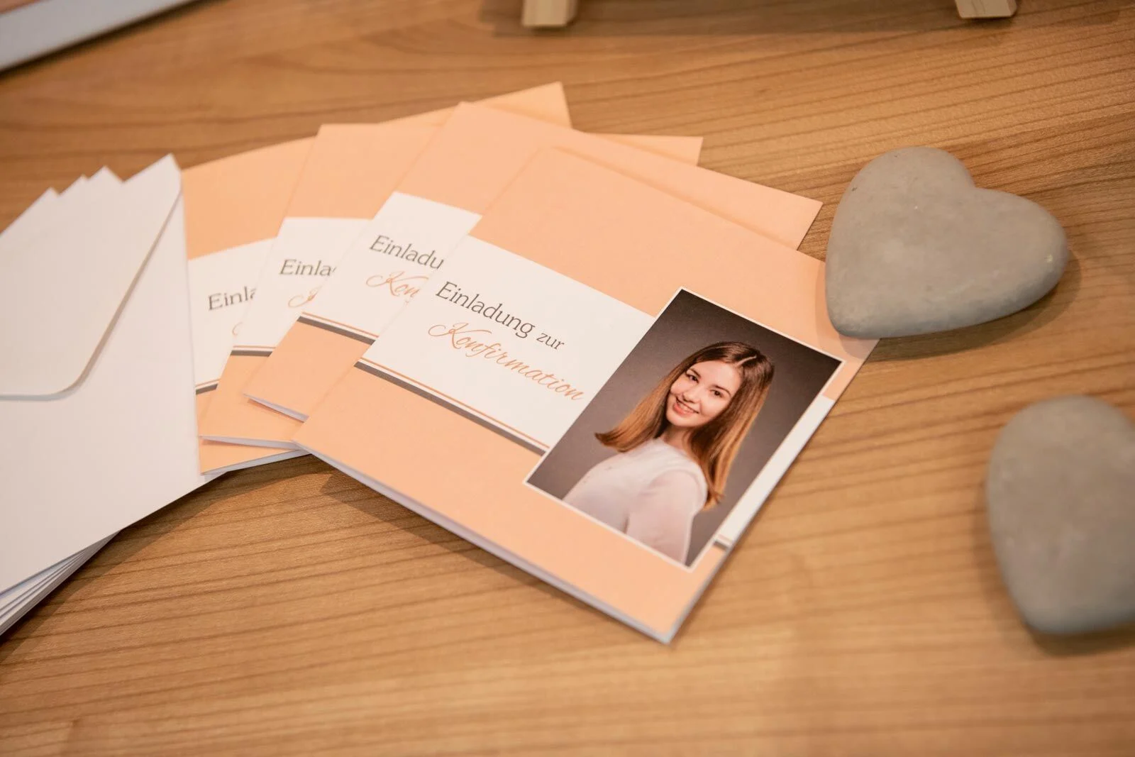 Einladungskarten zur Konfirmation in Pastell mit Portrait eines Mädchens, daneben Steinherzen