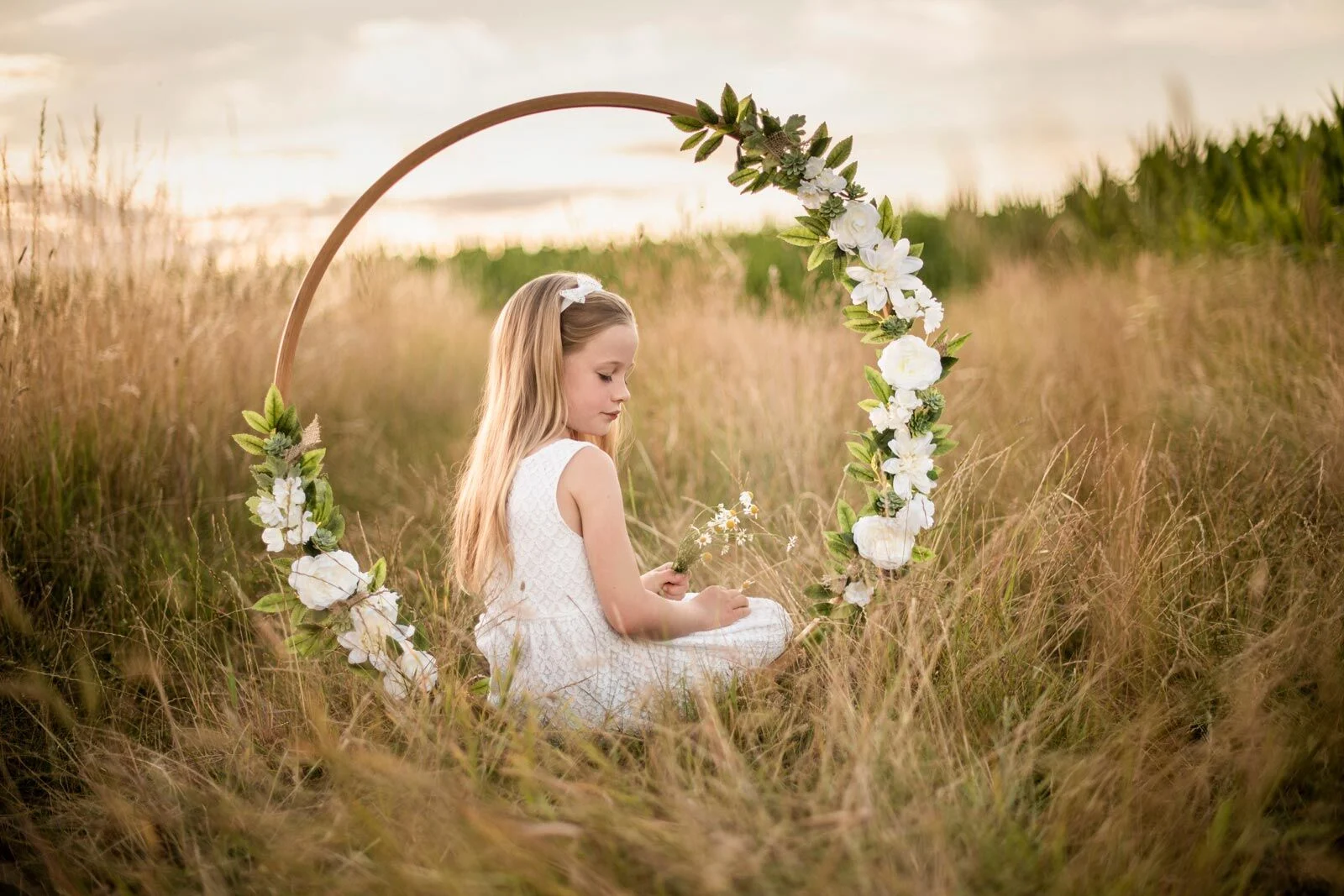 Versunken im Blumenring | Peter Lauritis Photography Mädchen mit Haarreif sitzt versunken in einem Blumenring im hohen Gras