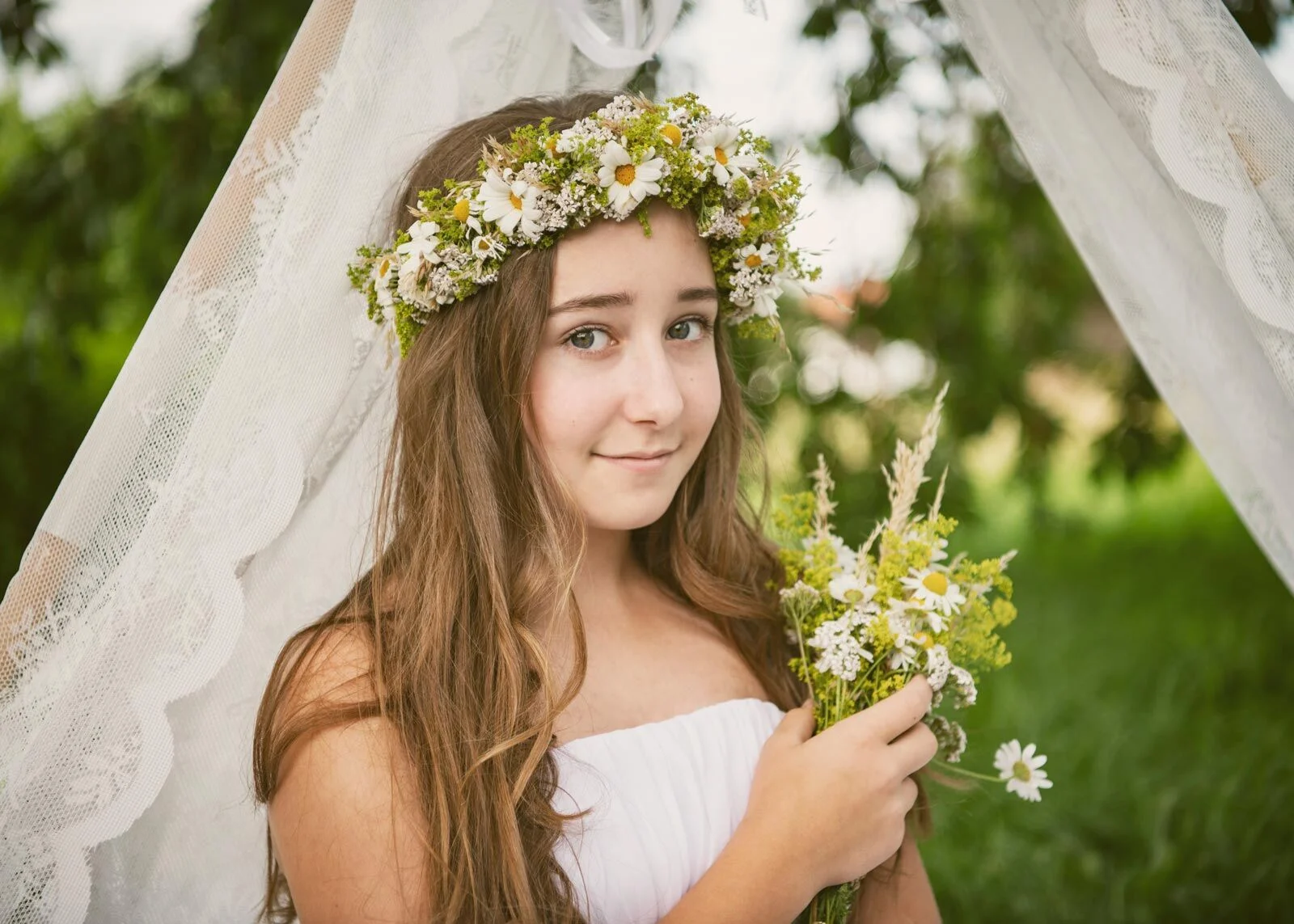 Vintage-Fotoaktion: Mädchen mit Blumenkranz hält einen Wiesenstrauß vor Spitzenstoff