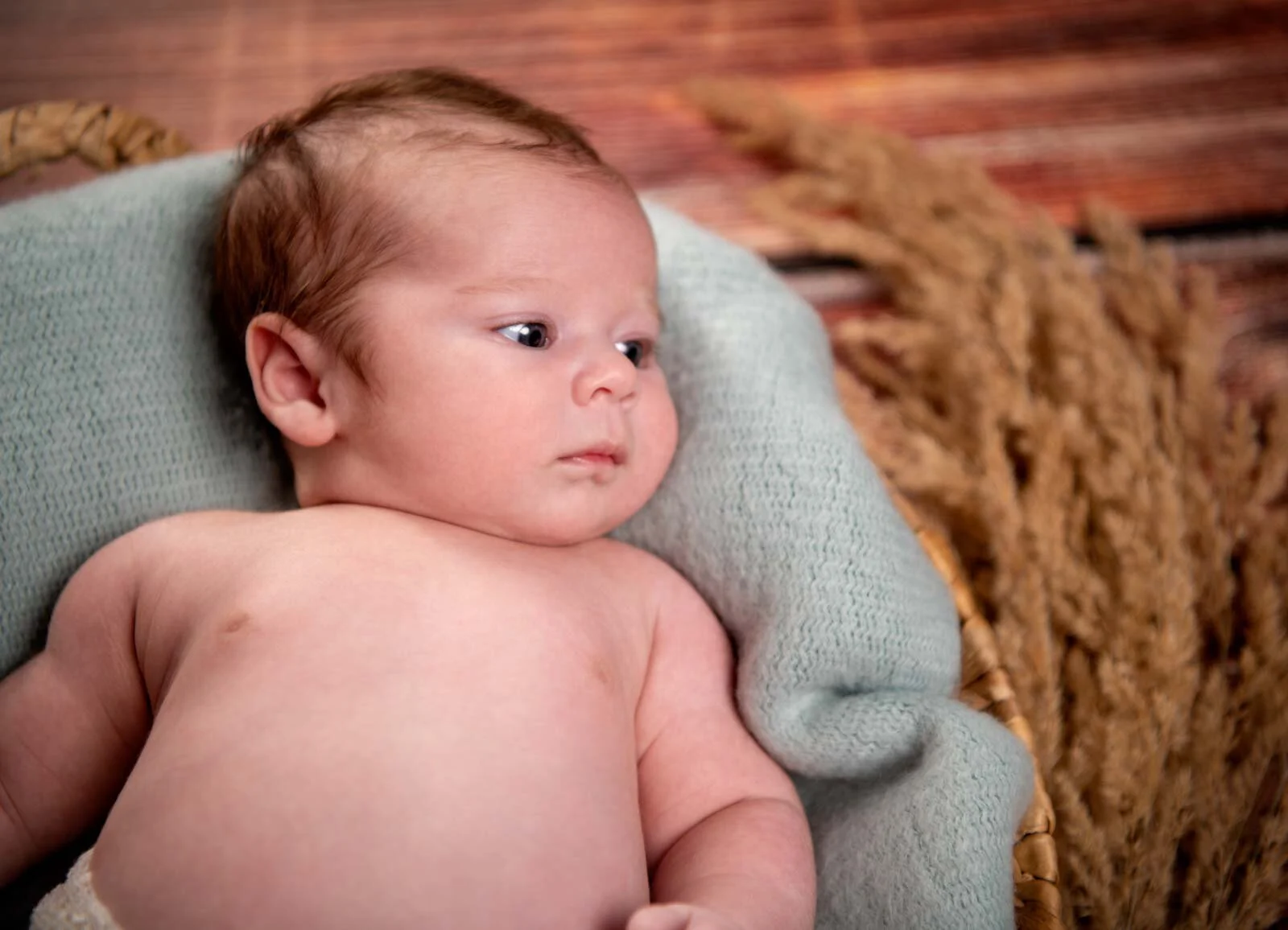 Nahaufnahme eines Babys auf grüner Decke, das neugierig zur Seite schaut