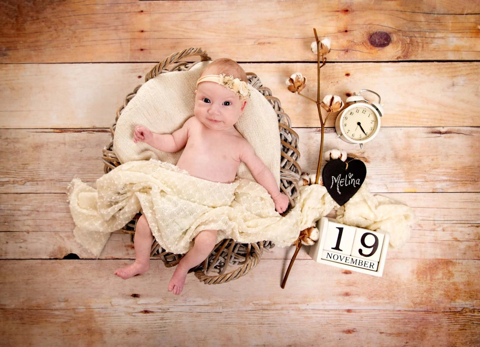 Von oben mit Details | Peter Lauritis Photography Baby im Weidenkorb von oben, daneben Wecker, Holzherz, Baumwolle und Datumswürfel