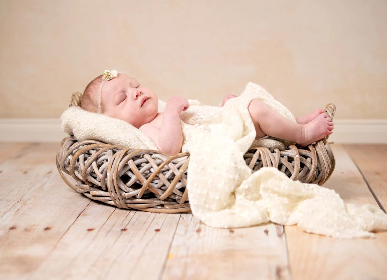 Im Weidenkorb | Peter Lauritis Photography Baby mit Haarband schläft in einem Weidenkorb auf cremefarbener Decke