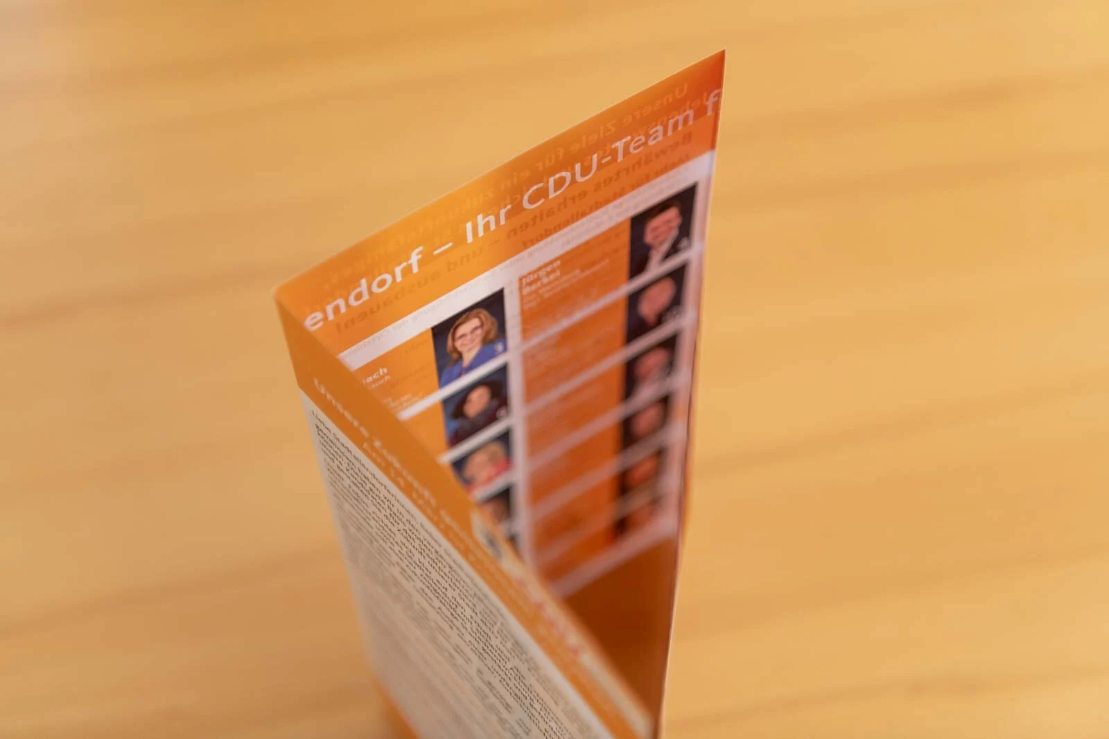 Aufgestellter Wahlflyer mit einer Reihe kleiner Portraits, seitlich fotografiert