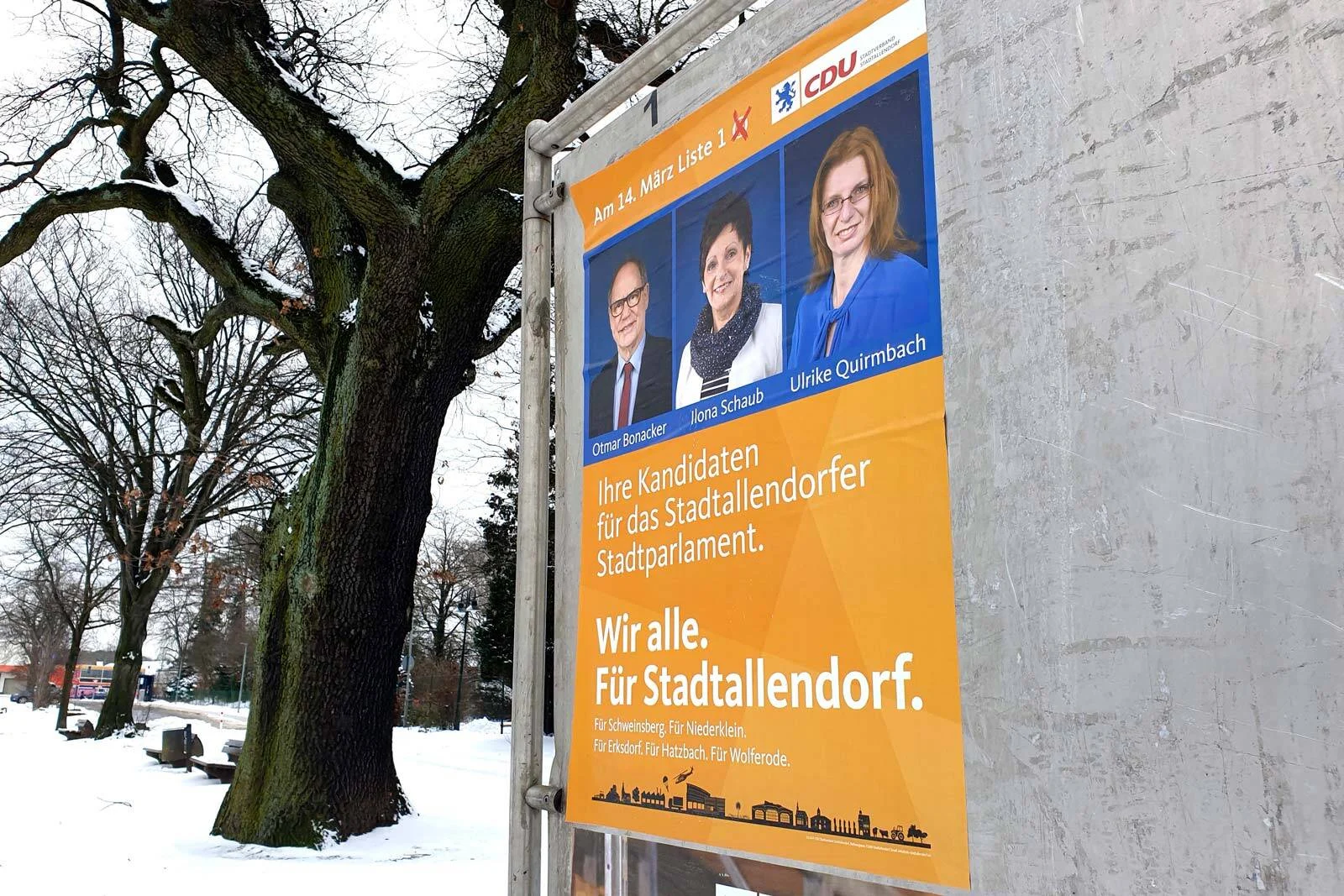 Großes CDU-Wahlplakat mit drei Portraits neben einem Baum im verschneiten Park