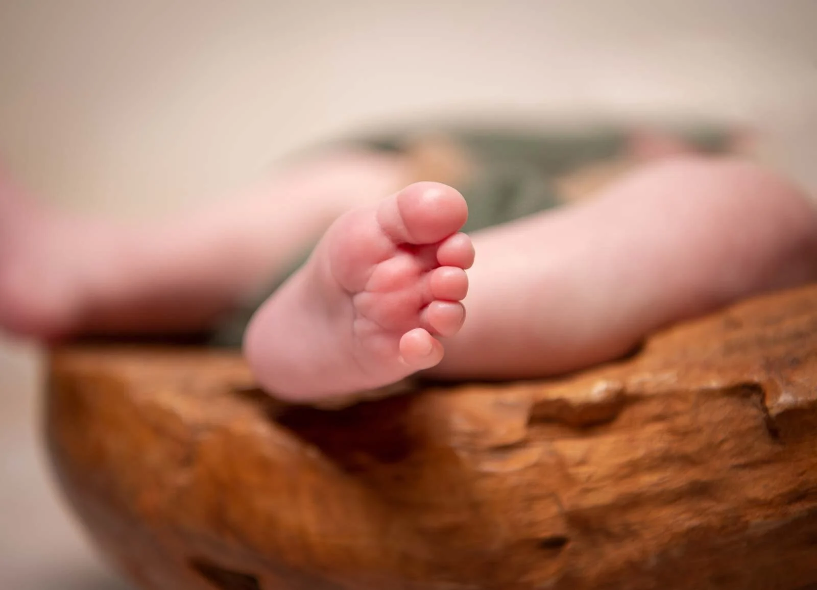 Nahaufnahme winziger Babyzehen am Rand einer hölzernen Schale