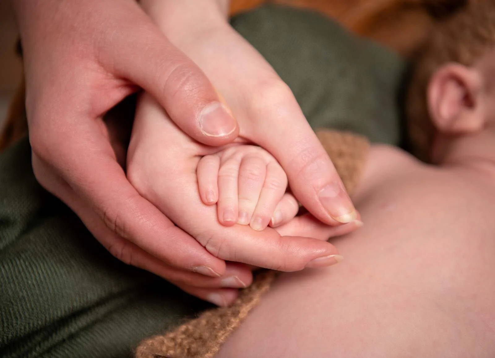 Die kleine Hand des Babys liegt in der Hand der Mutter