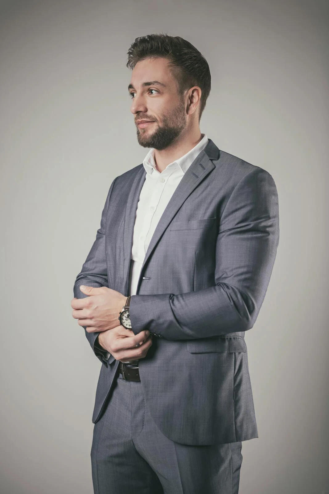 Männerportraits im Business-Style: Mann im Sakko schaut zur Seite und richtet seine Uhr