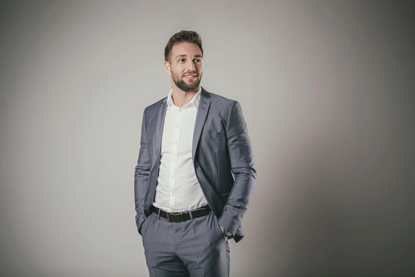 Mann im grauen Anzug steht entspannt mit einer Hand in der Hosentasche