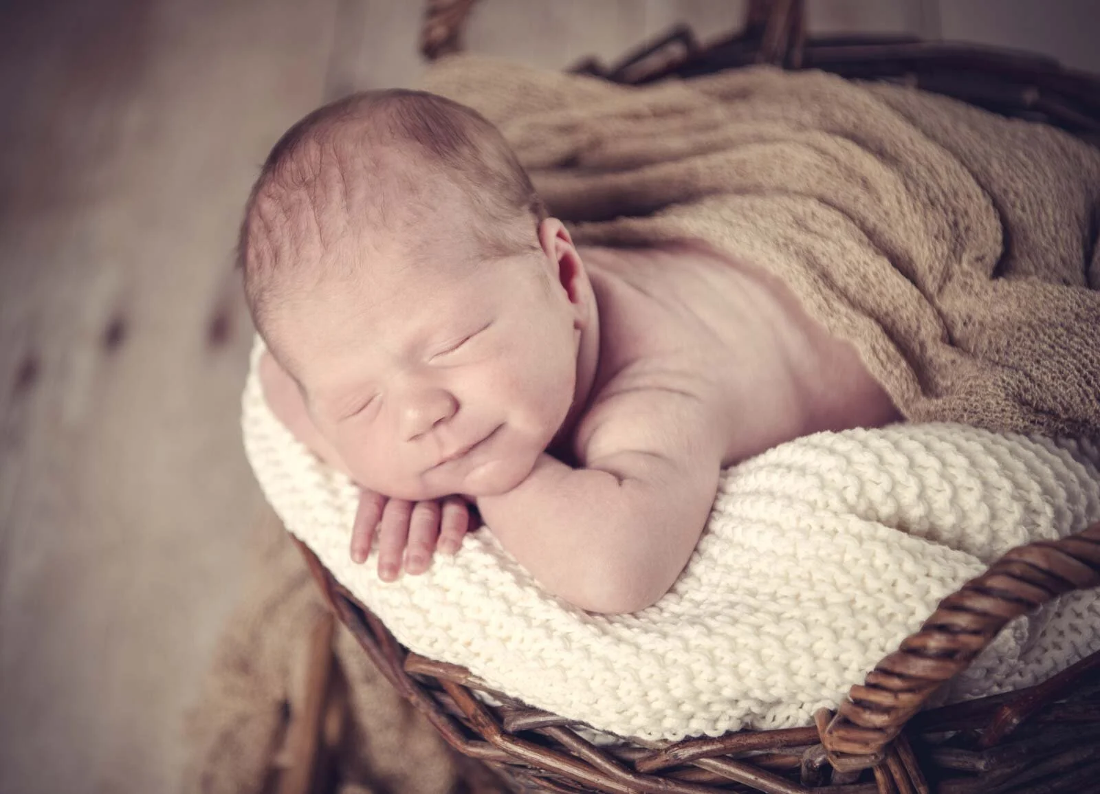 Newborn Fotoshooting: schlafendes Baby liegt mit dem Kopf auf den Händen auf einer Strickdecke