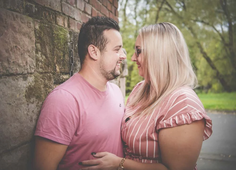Pärchen Fotoshooting: Paar in Rosa lehnt an einer alten Sandsteinmauer und schaut sich an