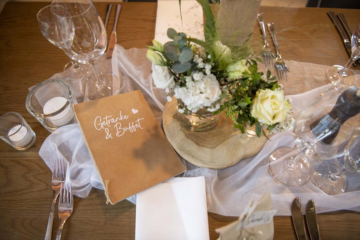 Karte mit der Aufschrift Getränke und Buffet neben Blumen und Gläsern
