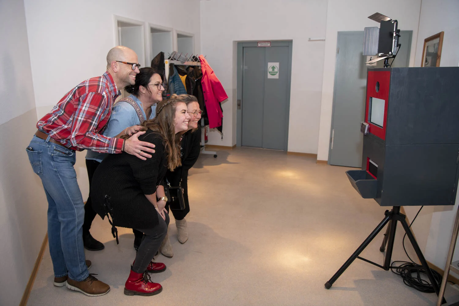 Gruppe posiert lachend vor einer Fotobox auf einem Stativ