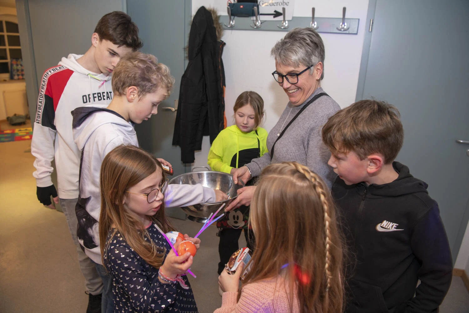 Kinder mit Leuchtstäben stehen um eine Frau mit einer Schüssel