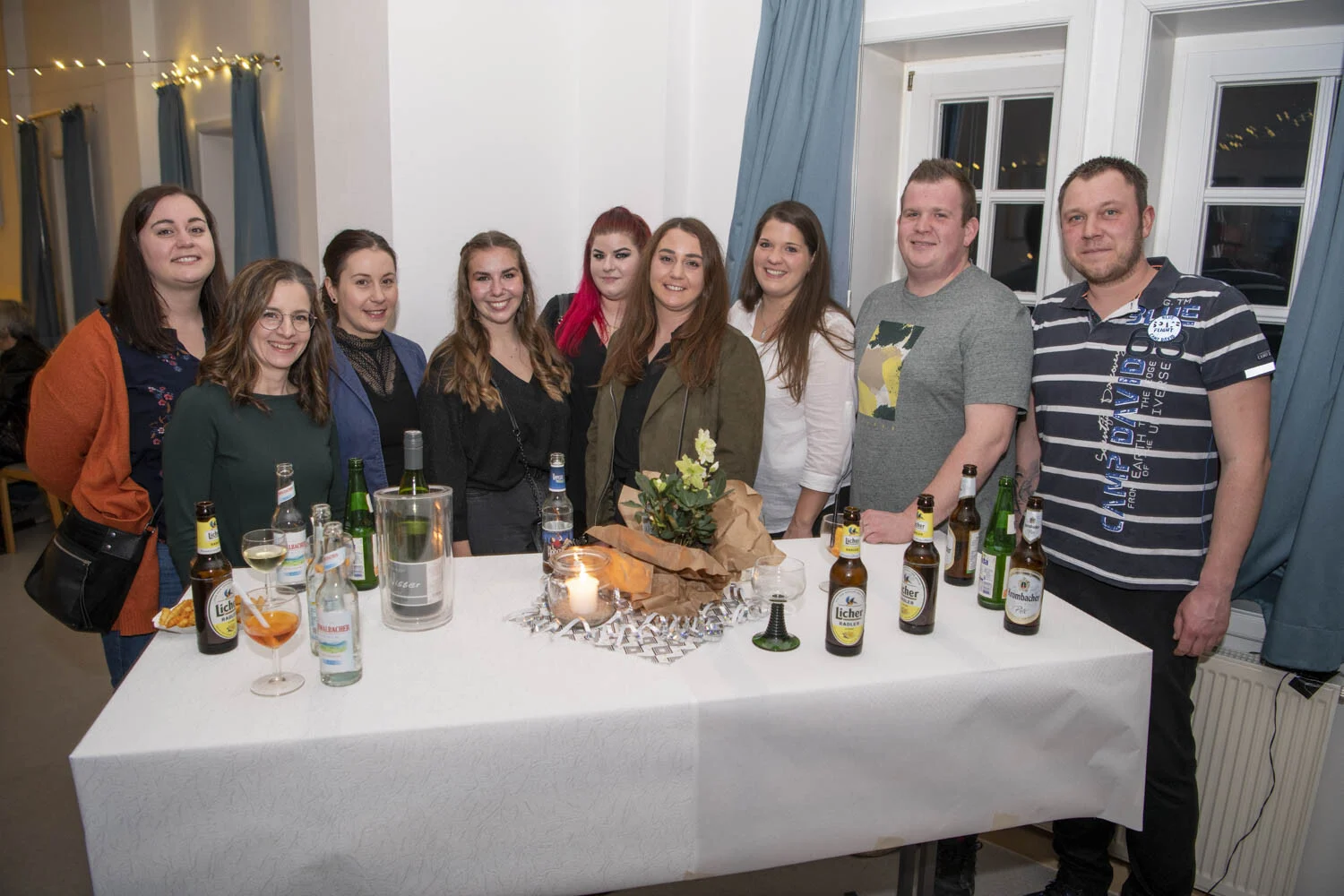 Gruppe junger Leute steht lächelnd an einem gedeckten Stehtisch