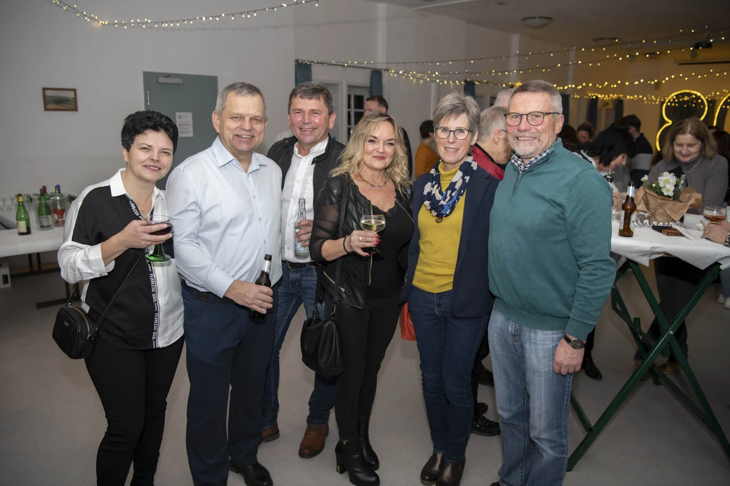 Gruppe von Gästen mit Gläsern lächelt in die Kamera