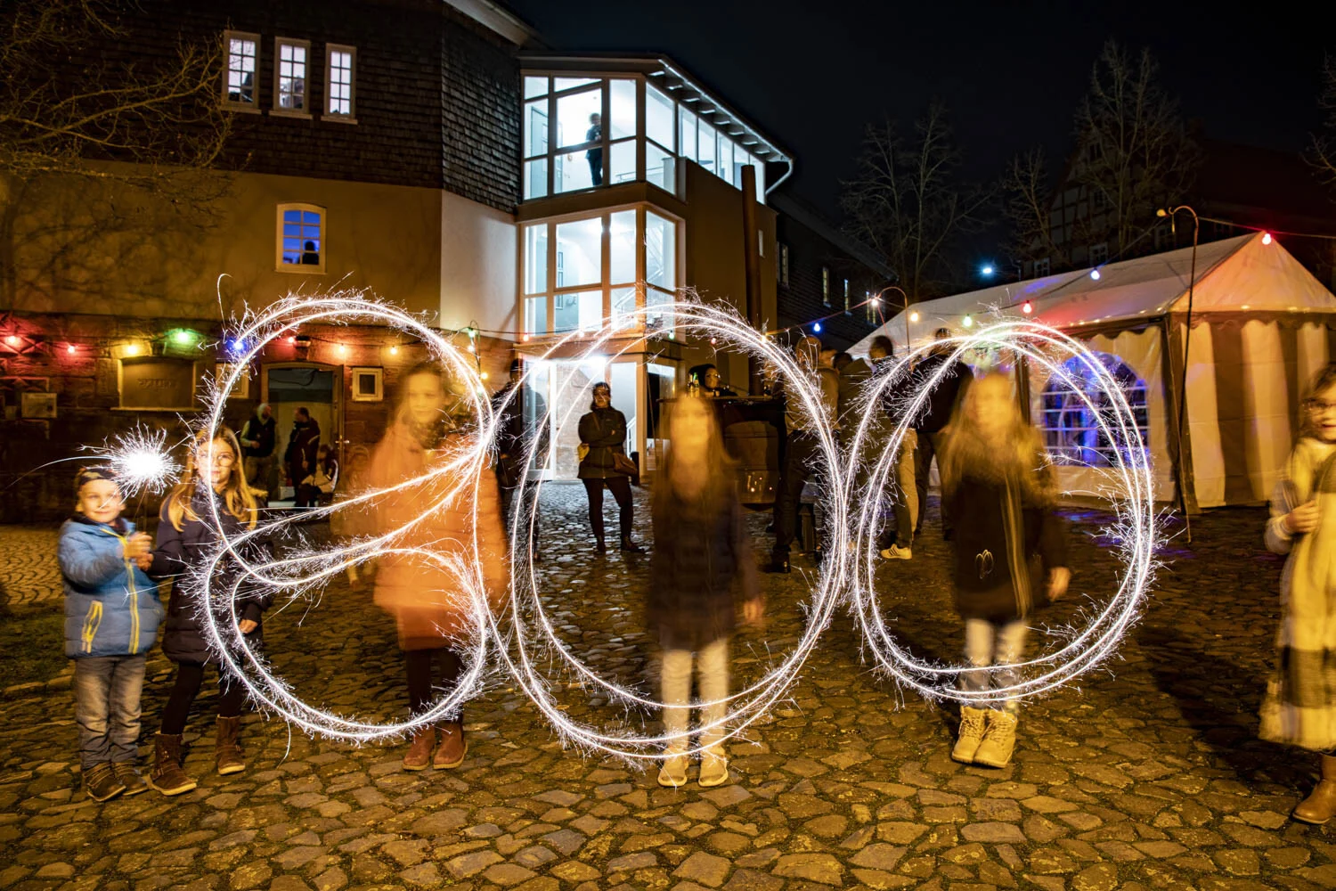 Silvesterfeier: mit Wunderkerzen gemalte Zahl 800 bei Nacht auf dem Dorfplatz