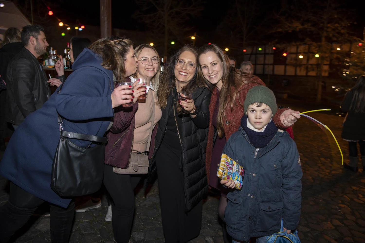 Frauen und ein Junge stoßen draußen in der Silvesternacht an