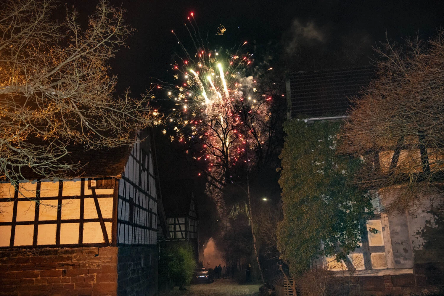Buntes Feuerwerk über einem Fachwerkhaus bei Nacht
