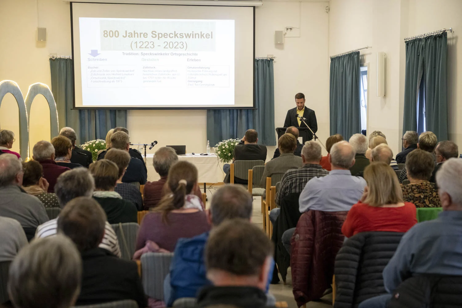 Buchvorstellung im Zollhof: voll besetzter Saal, vorn ein Redner vor der Leinwand