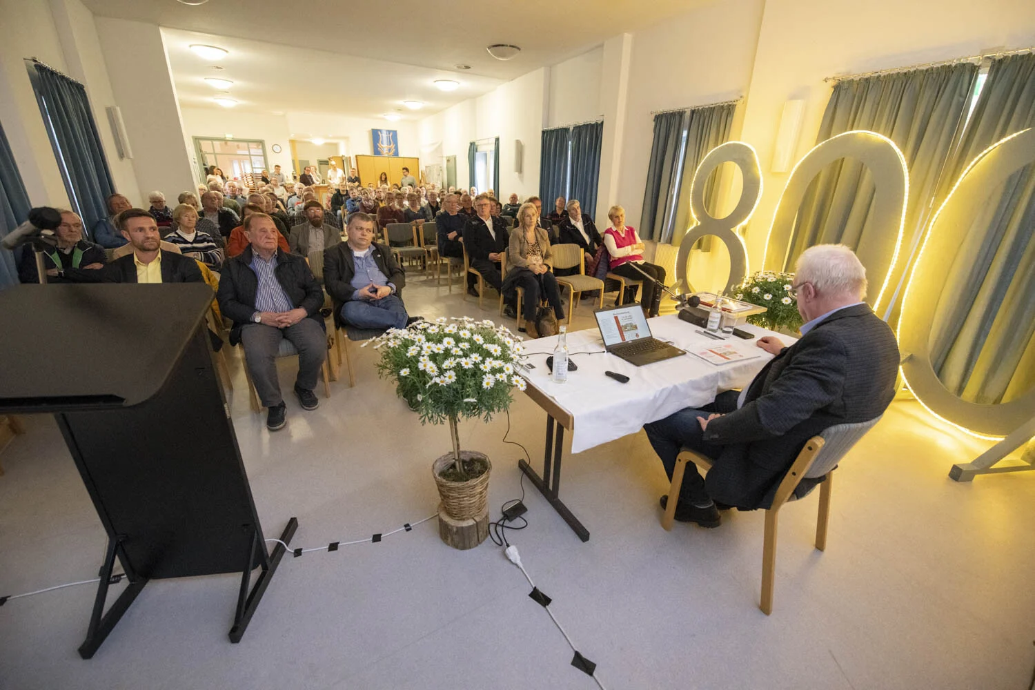 Autor am Tisch mit Laptop, daneben die leuchtende 800