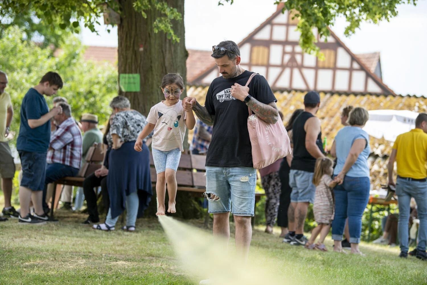 Gäste stehen im Schatten eines Baumes vor einem Fachwerkhaus