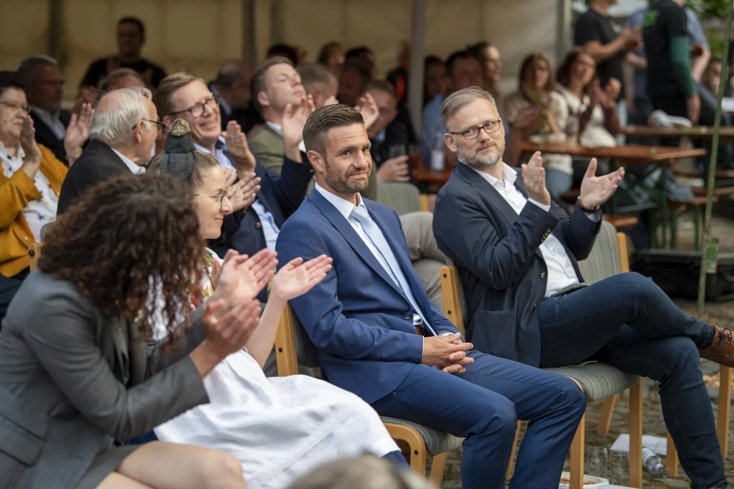 Gäste in der ersten Reihe applaudieren lächelnd