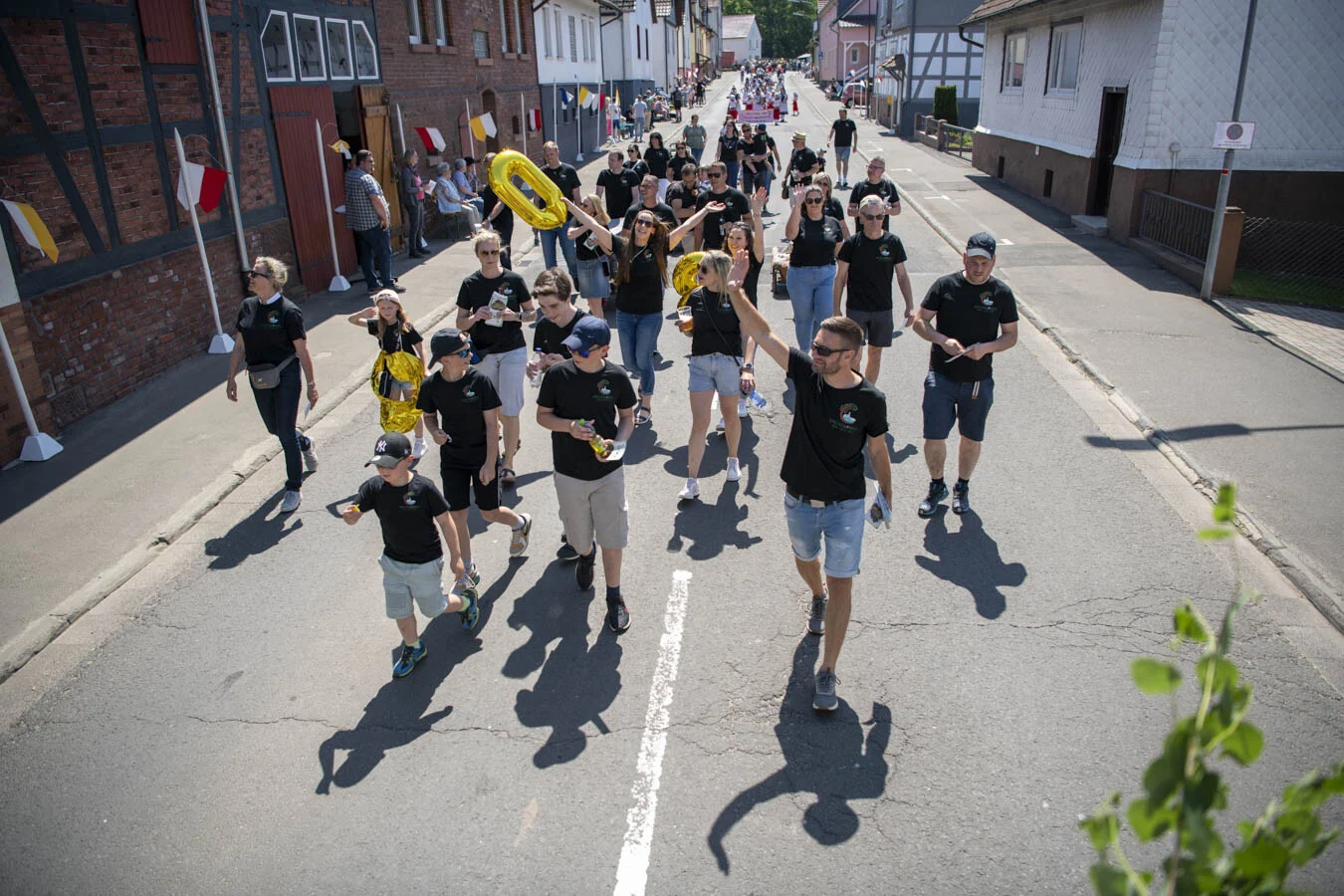 Teilnehmende in schwarzen Shirts laufen eine Straße entlang