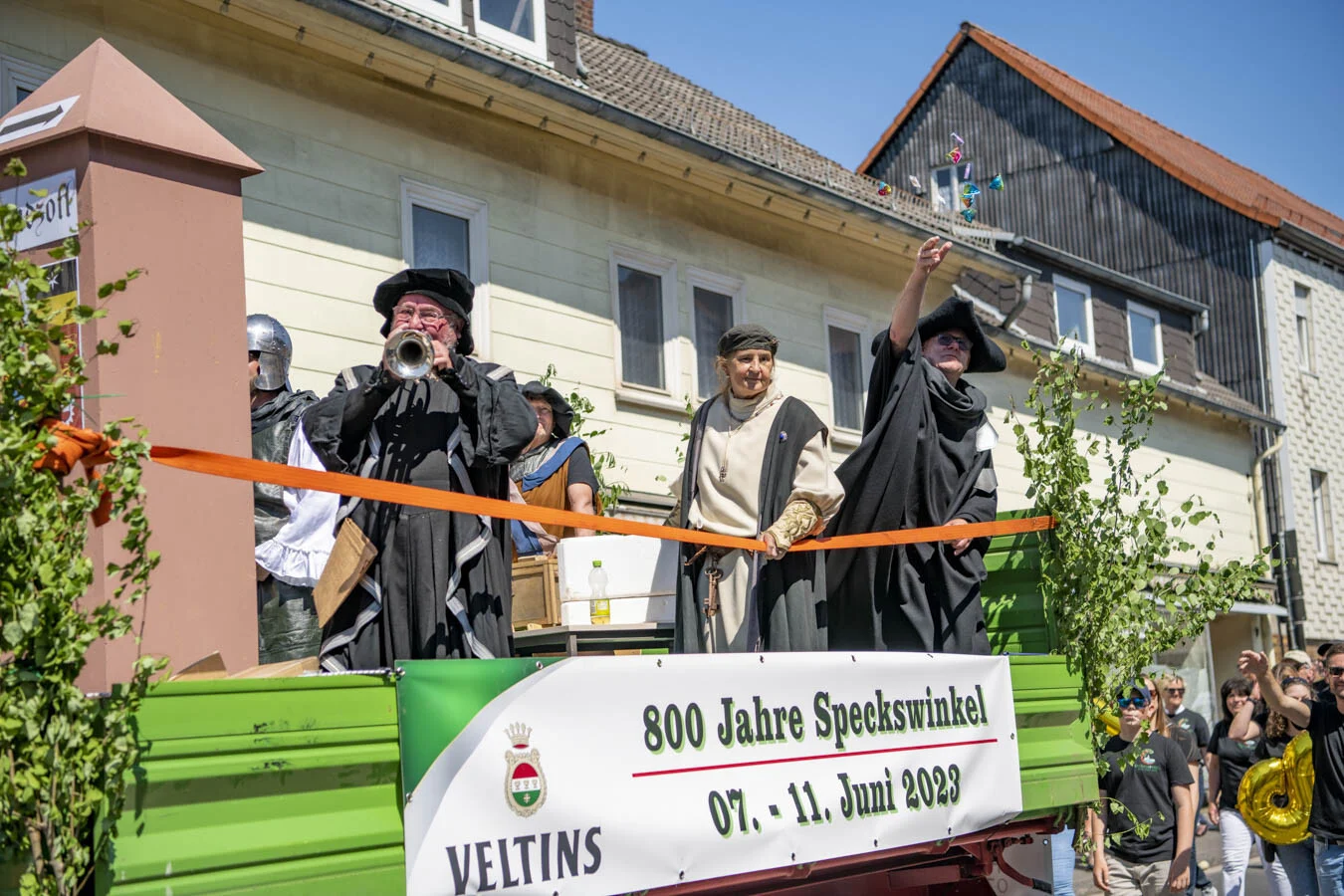 Darsteller spielt Trompete auf dem Festwagen mit Banner 800 Jahre Speckswinkel