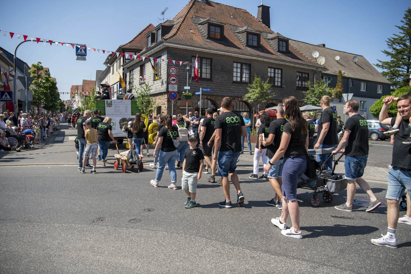 Festzug mit vielen Teilnehmenden an einer Straßenkreuzung