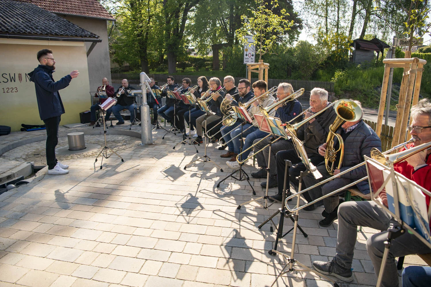 Posaunenchor spielt unter der Leitung eines Dirigenten auf einem gepflasterten Platz