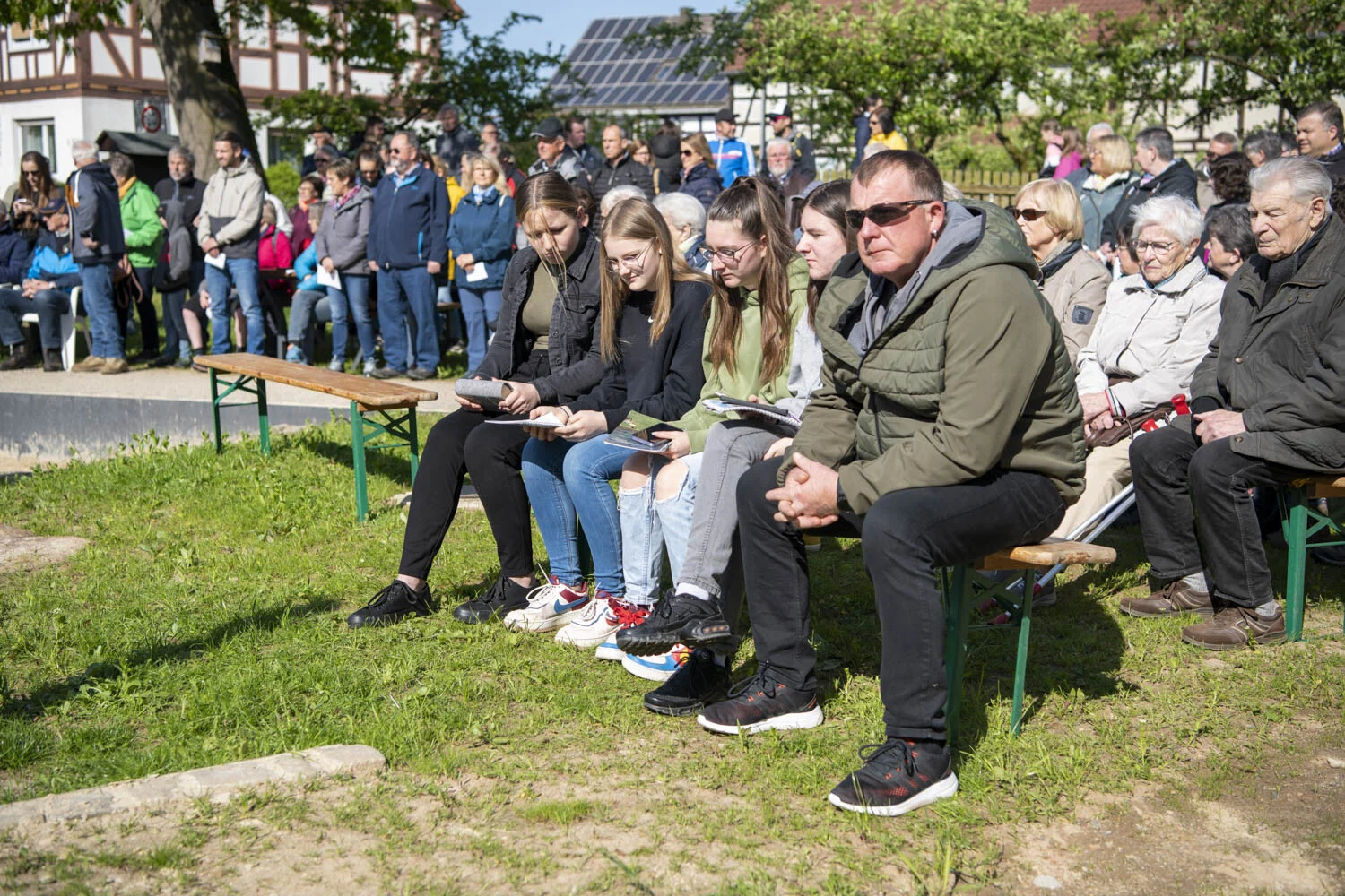 Zuhörerinnen und Zuhörer sitzen auf Bänken und lauschen der Andacht
