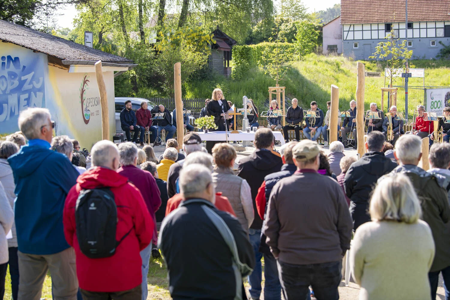 Gäste stehen vor einer Bühne mit Rednerpult auf der Wiese