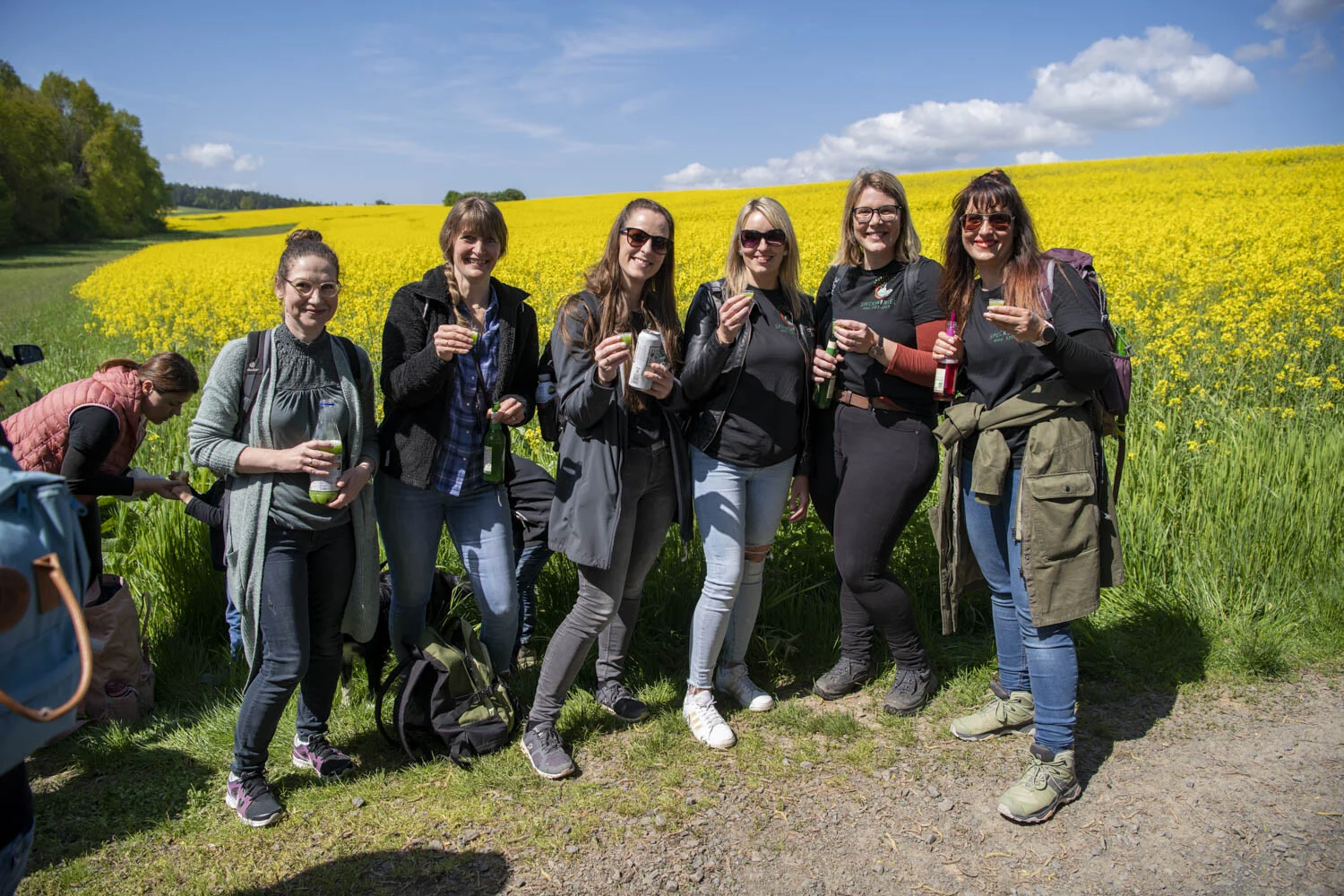Gruppe von Frauen steht lachend vor einem blühenden gelben Rapsfeld