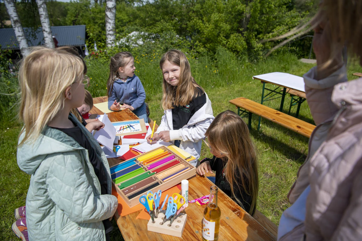 Mädchen malen mit Buntstiften an einem Tisch im Freien