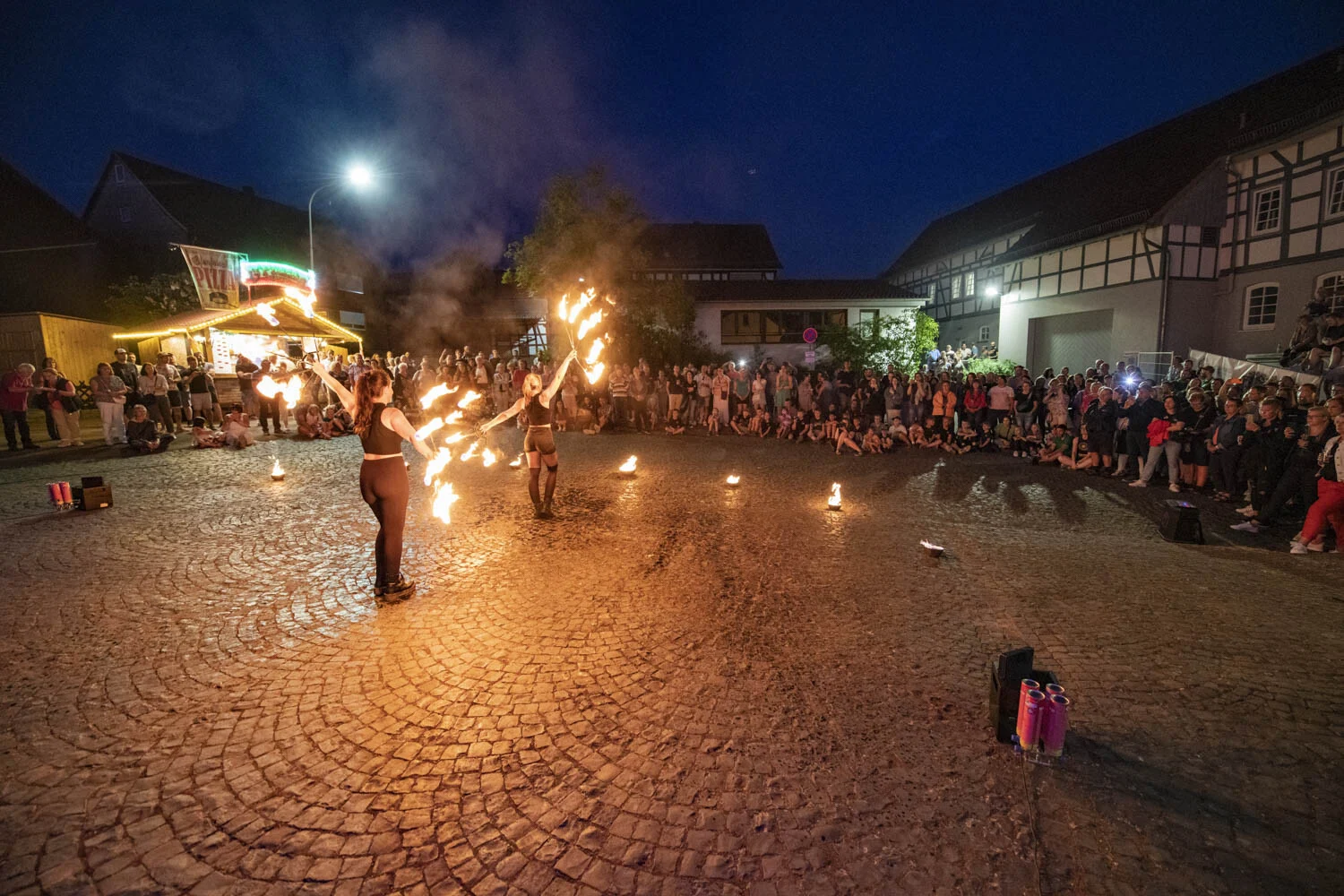 Zwei Artistinnen mit brennenden Feuerfächern auf dem Kopfsteinpflaster